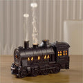 Black train aroma diffuser with steam-like mist on a table